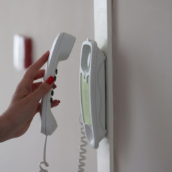 Nous installons le système de communication à distance entre le résident et le visiteur Une main de femme décroche le récepteur de l'interphone dans un appartement.