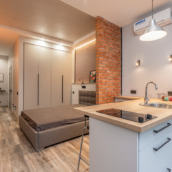 Nous étudions vos demandes et réalisons des solutions adaptées aux meilleures conditions Vue d'un logement de une pièce avec éclairage, kitchenette, climatisation